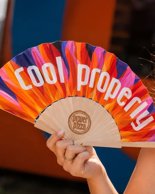 A printed hand fan reading cool properly
